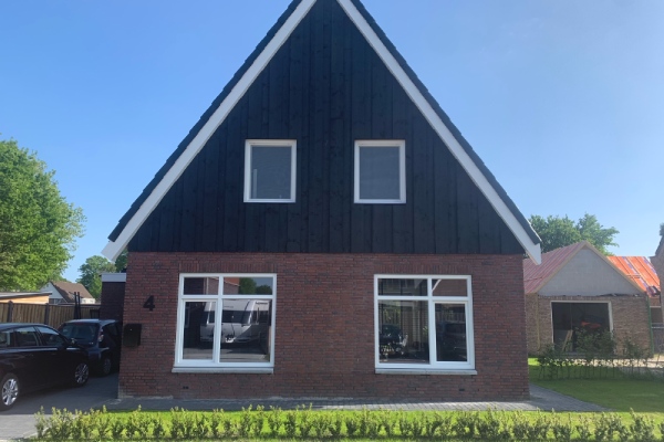 Moderne woning met kunststof kozijnen in de voorgevel, combinatie van rode bakstenen en zwart hout